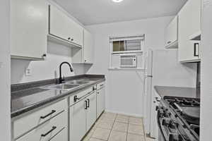 Kitchen featuring sink, light tile patterned floors, white cabinetry, cooling unit, and stainless steel range with gas cooktop