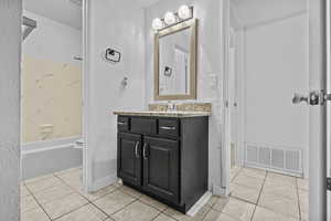 Bathroom featuring tile patterned flooring, vanity, and shower / bathtub combination