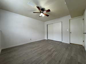 Unfurnished bedroom featuring hardwood / wood-style floors, a closet, and ceiling fan