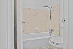 Bathroom featuring tile patterned floors, shower / bathtub combination, and toilet