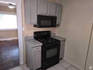 Kitchen featuring light tile patterned floors, gray cabinets, ceiling fan, and black appliances