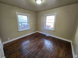 Unfurnished room featuring dark hardwood / wood-style flooring and plenty of natural light