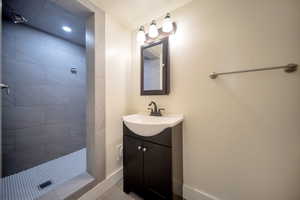 Bathroom with tile patterned flooring, a tile shower, and vanity