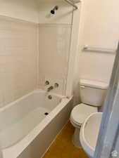 Bathroom with tile patterned floors, tiled shower / bath combo, and toilet