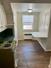 Kitchen featuring radiator, electric range, and dark hardwood / wood-style flooring