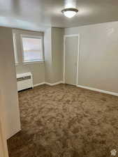 Carpeted spare room with radiator heating unit