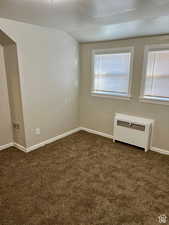 Carpeted empty room featuring radiator