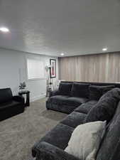 Carpeted living room with wood walls and a textured ceiling