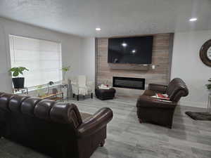 Living room with a large fireplace, light wood-type flooring, and a textured ceiling