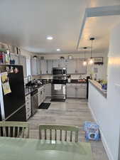 Kitchen featuring gray cabinetry, decorative light fixtures, stainless steel appliances, and tasteful backsplash