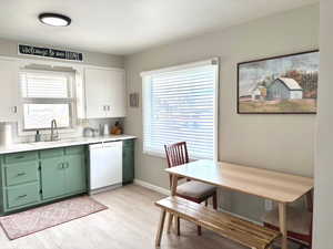 Updated kitchen featuring white cabinets, sink, light hardwood / wood-style flooring, green cabinetry, and dishwasher