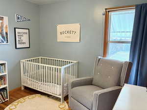 Bedroom with hardwood / wood-style flooring and a crib