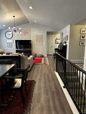 Living room featuring a chandelier, a textured ceiling, dark wood-type flooring, and lofted ceiling