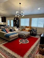 Living room with hardwood / wood-style floors, a notable chandelier, and a textured ceiling