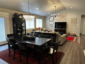 Dining area with hardwood / wood-style flooring, lofted ceiling, a textured ceiling, and a chandelier