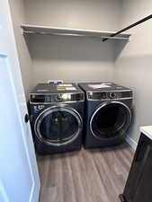 Washroom with washer and clothes dryer and wood-type flooring