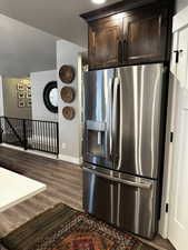 Kitchen with stainless steel fridge with ice dispenser, dark brown cabinetry, dark hardwood / wood-style floors