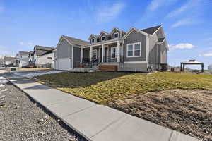 View of front of property featuring a front lawn, cooling unit, a gazebo, a porch, and a garage