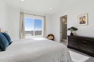 Bedroom with a water view, light colored carpet, and connected bathroom