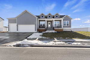 View of front facade featuring a front lawn, covered porch, and a garage