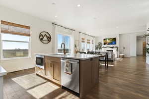 Kitchen with dark hardwood / wood-style flooring, a kitchen island with sink, sink, and appliances with stainless steel finishes