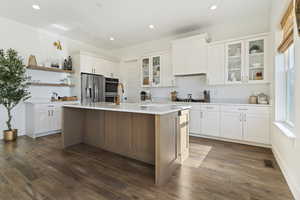 Kitchen with a center island with sink, white cabinets, dark wood-type flooring, and appliances with stainless steel finishes