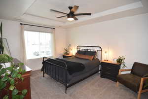 Carpeted Master bedroom featuring a raised ceiling and ceiling fan