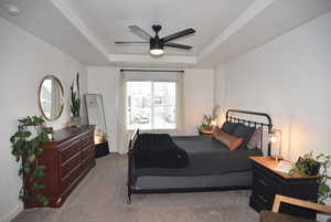 Carpeted Master bedroom with ceiling fan and a raised ceiling