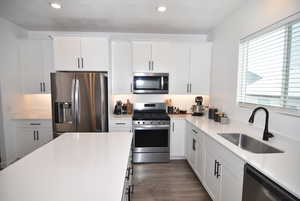 Kitchen featuring sink, white cabinets, and appliances with stainless steel finishes