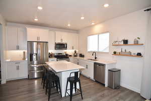 Kitchen with a kitchen bar, sink, white cabinets, and stainless-steel appliances