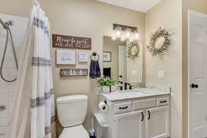 Bathroom featuring a shower with shower curtain, vanity, and toilet