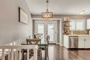 Dining room with french doors, a healthy amount of sunlight, a textured ceiling, and an inviting chandelier