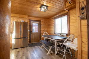 Dining space with log walls, light wood-type flooring, and wooden ceiling