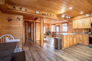 Kitchen with light stone countertops, light brown cabinets, wooden ceiling, and wood walls