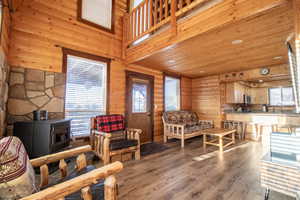 Living room featuring a wood stove, sink, log walls, a towering ceiling, and light wood-type flooring