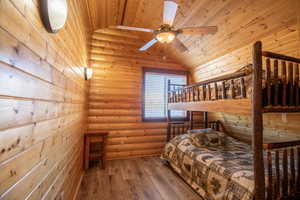 Bedroom featuring wood ceiling, ceiling fan, log walls, hardwood / wood-style floors, and lofted ceiling