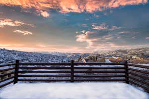 Snow covered patio with a mountain view and a balcony