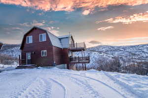 Snow covered rear of property with a mountain view and a balcony