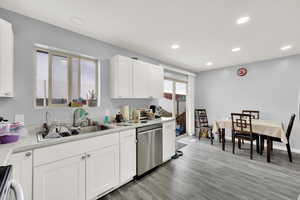 Kitchen with light wood-type flooring, stainless steel dishwasher, sink, range, and white cabinetry