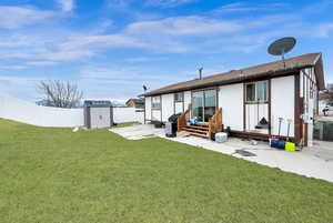 Rear view of house featuring a lawn, central AC unit, a storage shed, and a patio