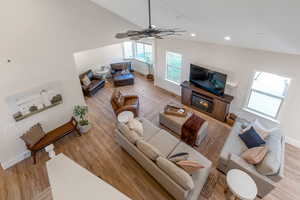 Living room with ceiling fan, light hardwood / wood-style floors, and vaulted ceiling