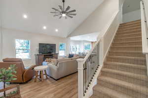 Living room with ceiling fan, high vaulted ceiling, and light hardwood / wood-style flooring