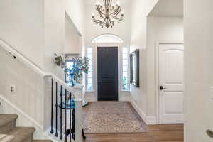 Foyer entrance featuring hardwood / wood-style floors, a high ceiling, and a notable chandelier