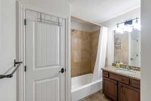 Bathroom featuring wood-type flooring, vanity, and shower / tub combo with curtain