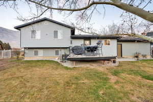 Rear view of property featuring a deck with mountain view and a lawn