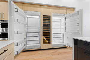 Kitchen featuring light brown cabinets, modern cabinets, double oven, and light wood-style floors
