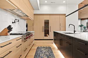 Kitchen featuring modern cabinets, light stone counters, recessed lighting, stainless steel gas stovetop, and light wood finished floors