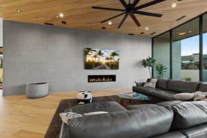 Living room with wood ceiling, a warm lit fireplace, recessed lighting, wood finished floors, and a ceiling fan
