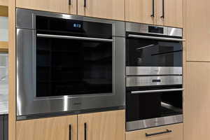Kitchen with light brown cabinetry, double oven, and modern cabinets