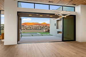 Doorway to outside featuring a high ceiling, a mountain view, a fireplace, wood ceiling, and light wood-type flooring